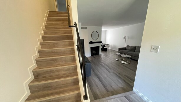 Un escalier menant à un espace de vie comprenant un canapé, une table basse et une cheminée.