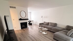 Un salon moderne avec un téléviseur à écran plat, un canapé, une table basse et une cheminée.