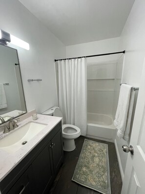 A bathroom with a sink, toilet, bathtub, and a shower curtain.