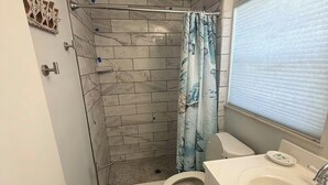 Een kleine badkamer met douche, toilet en wastafel.