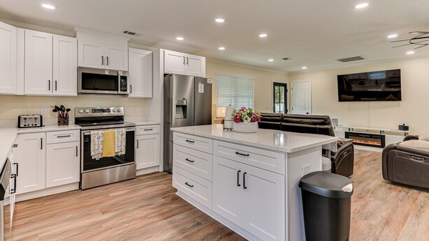 A modern kitchen with white cabinetry, stainless steel appliances, and a central island.