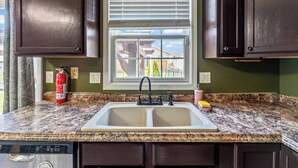 A kitchen with a double sink, a window with blinds, and a dish soap bottle on the counter. - Blue Moon Ranch in Bloomington (Bloomington)