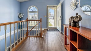 A hallway with a wooden staircase, a door leading outside, and a decorative elephant sculpture on a wooden console. - Blue Moon Ranch in Bloomington (Bloomington)