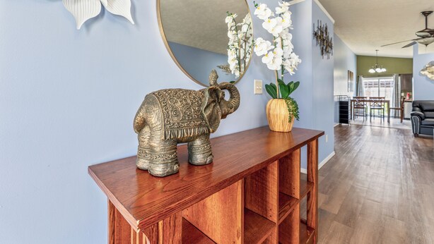 A living room with a wooden console table, an elephant sculpture, a mirror, and white orchids. - Blue Moon Ranch in Bloomington (Bloomington)