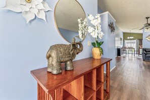 A living room with a wooden console table, an elephant sculpture, a mirror, and white orchids.