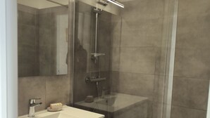 A modern bathroom with a glass-enclosed shower, a white sink, and a mirror with integrated lighting. - Seaside studio in Moriani (San-Nicolao)