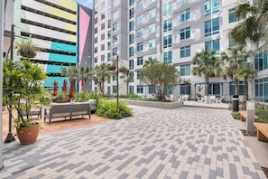 Une cour avec un chemin pavé, des bancs, des plantes en pot et des espaces pour s’asseoir à l’extérieur.