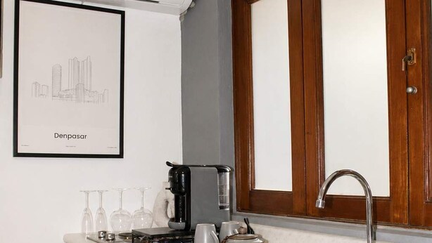 A modern kitchen with a built-in sink, wooden cabinets, and a framed cityscape picture on the wall. - Suite Privada Totalmente Equipada (Zapopan)