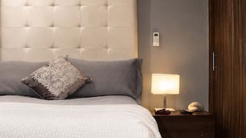 Un dormitorio con cabecera capitonada, lámpara de noche y armario de madera.