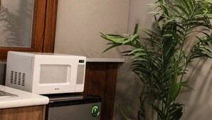 A compact kitchenette with a microwave, a refrigerator, and a potted plant. - Suite Privada Totalmente Equipada (Zapopan)
