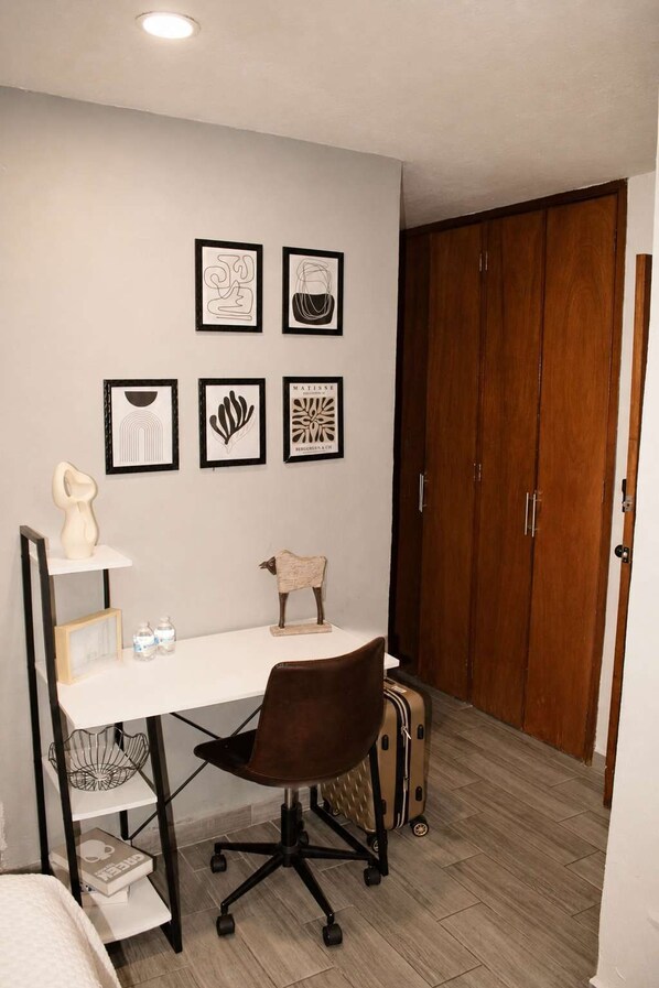 Ein Zimmer mit Schreibtisch, Stuhl und einem Bild an der Wand.