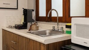 A kitchen with wooden cabinets, a stainless steel sink, a microwave, and a coffee maker. - Suite Privada Totalmente Equipada (Zapopan)