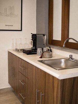A modern kitchen with a built-in sink, a coffee maker, and wine glasses on the counter. - Suite Privada Totalmente Equipada (Zapopan)