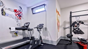 Un gimnasio con cintas de correr, bicicletas estáticas y una zona de pesas.