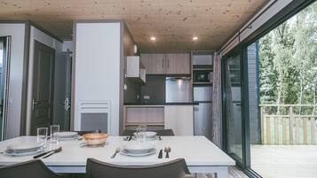 A modern kitchen with built-in appliances, a dining table set for four, and a large sliding glass door leading to an outdoor deck.