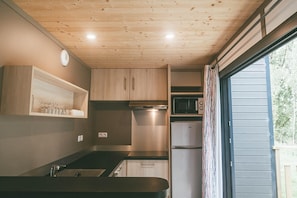 Una cocina compacta con armarios de madera, microondas y un refrigerador pequeño.