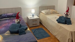 A bedroom with two beds, a nightstand with a lamp, and two gnome decorations. - Apartment with large panoramic terrace (Traona)
