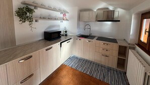 A compact kitchen with a microwave, coffee maker, and a sink. - Apartment with large panoramic terrace (Traona)