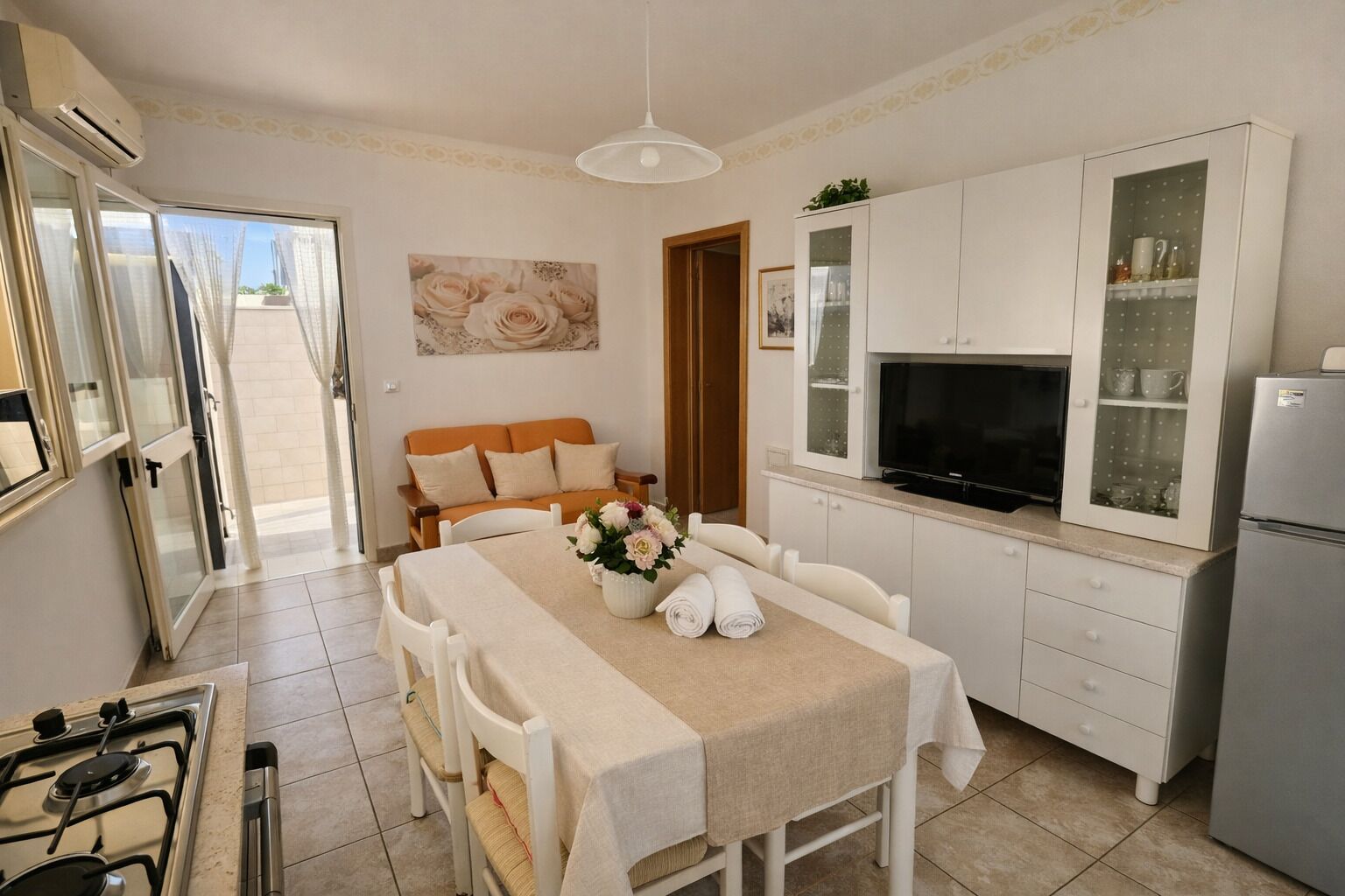 A compact kitchen with a dining area, a sofa, and a TV.