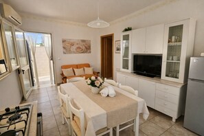 A compact kitchen with a dining area, a sofa, and a TV. - Beach House 50m from the Sea | 2 Bedrooms, 2 Bathrooms, Air Conditioning (Torre Pali)