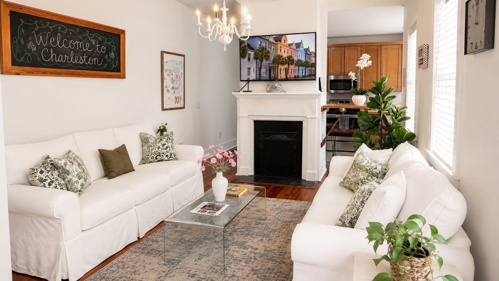 A living room with a white sofa set, a coffee table, a fireplace, and a television.