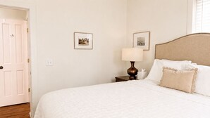 Una camera d'albergo con un letto, un comodino, una lampada e due quadri appesi al muro.