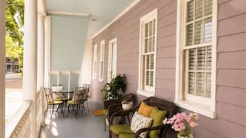 A covered porch with a striped floor, wicker furniture, and a potted plant.