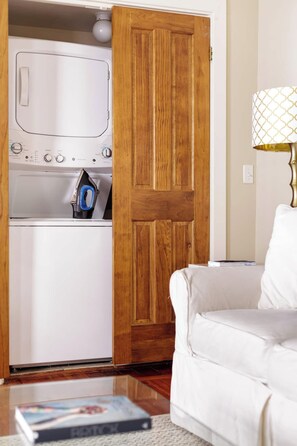 A laundry room with a wooden door, a washing machine, and an iron. - The Fig House on Spring · Walk to King · 3BR, Sleeps 8 (Charleston)