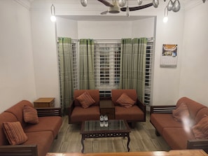 Una sala de estar con dos sofás, una mesa de centro y un ventanal con cortinas.