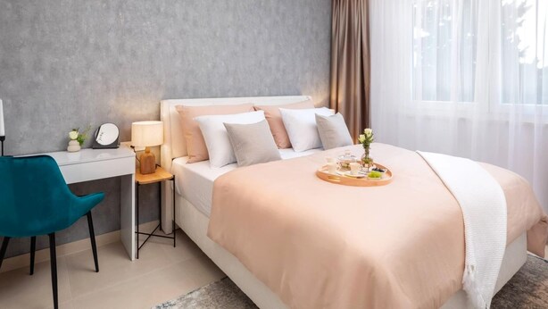 Una habitación de hotel moderna con una cama, un escritorio, una silla y una ventana con cortinas.
