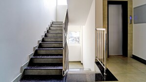 A staircase leading to an upper floor, a door with a view, and a wall-mounted control panel. - Deluxe Super Townhouse Oak Cochin (Aluva)