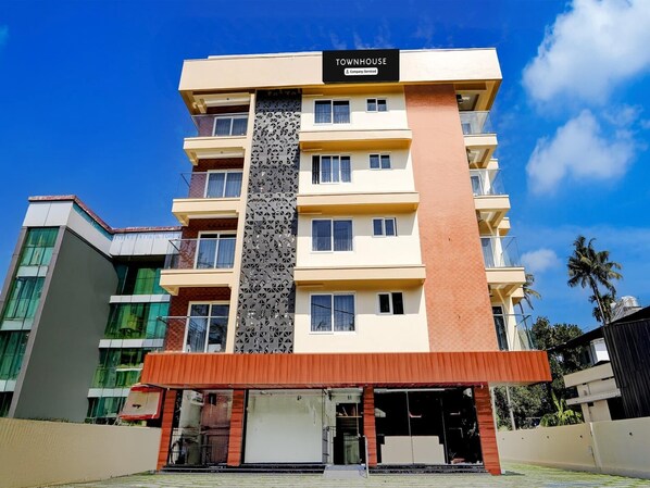 A multi-story building with a sign reading 'TOWNHOUSE' and a 'Company Serviced' label. - Deluxe Super Townhouse Oak Cochin (Aluva)
