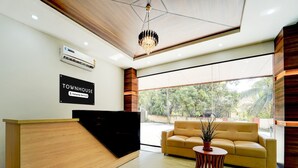 A reception area with a wooden reception desk, a sofa, a potted plant, and a sign that reads 'TOWNHOUSE Company-Serviced.' - Deluxe Super Townhouse Oak Cochin (Aluva)