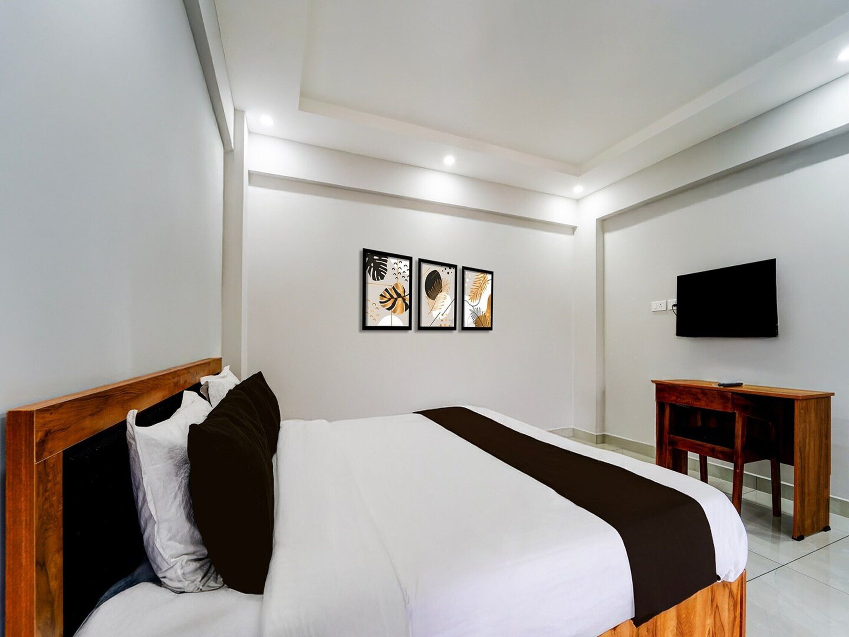 A modern hotel room with a large bed, a desk, and a flat-screen TV.