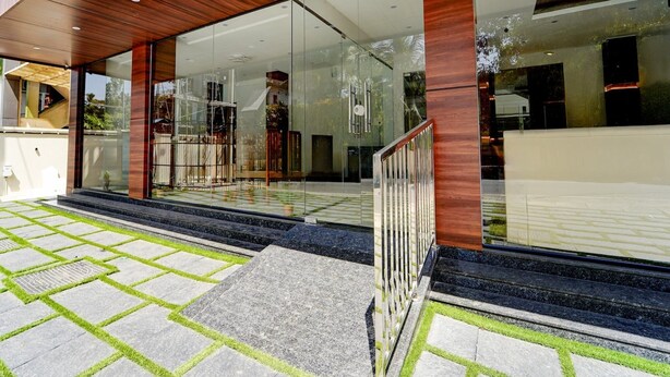 A modern building with large glass windows, a wooden facade, and a stone-paved entrance area. - Deluxe Super Townhouse Oak Cochin (Aluva)