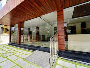 A modern building with large glass windows, a wooden facade, and a stone-paved entrance area. - Deluxe Super Townhouse Oak Cochin (Aluva)