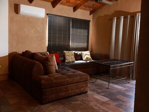 A living room with a brown leather sofa, a small table, and a window with blinds.