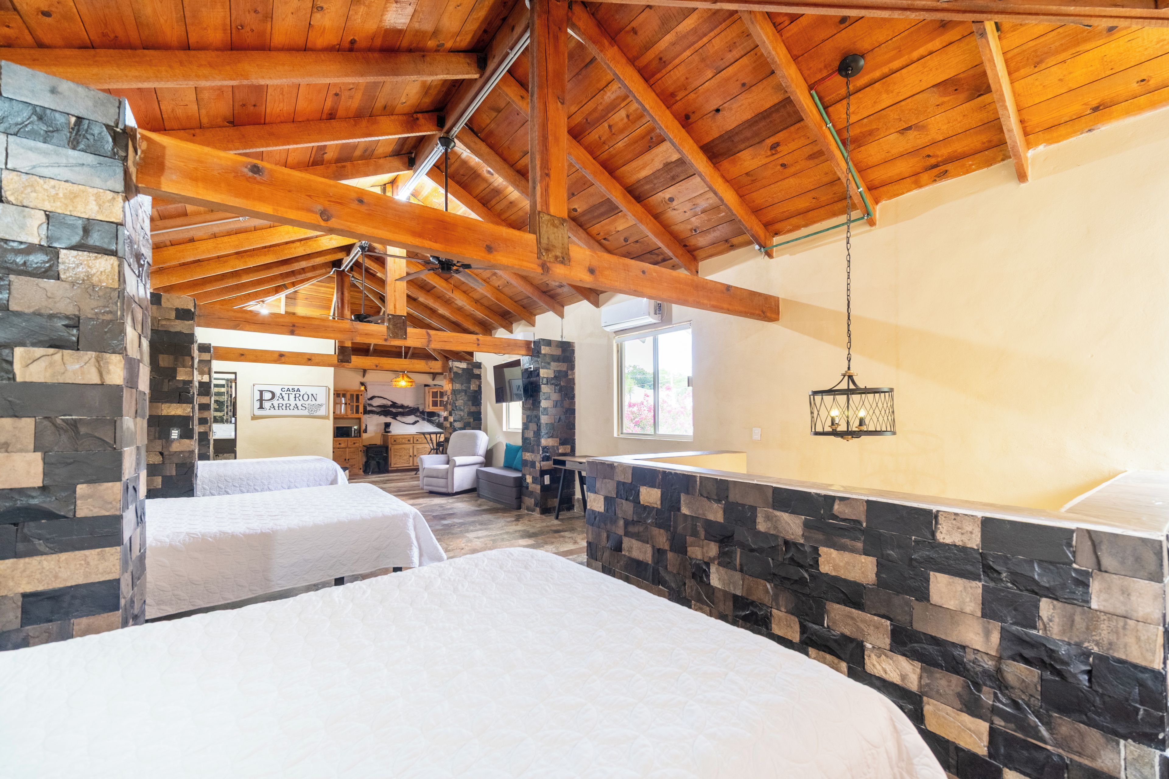 Una camera d'albergo con soffitto in legno alto, pareti in pietra e due letti.