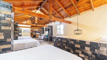 Una camera d'albergo con soffitto in legno alto, pareti in pietra e due letti.