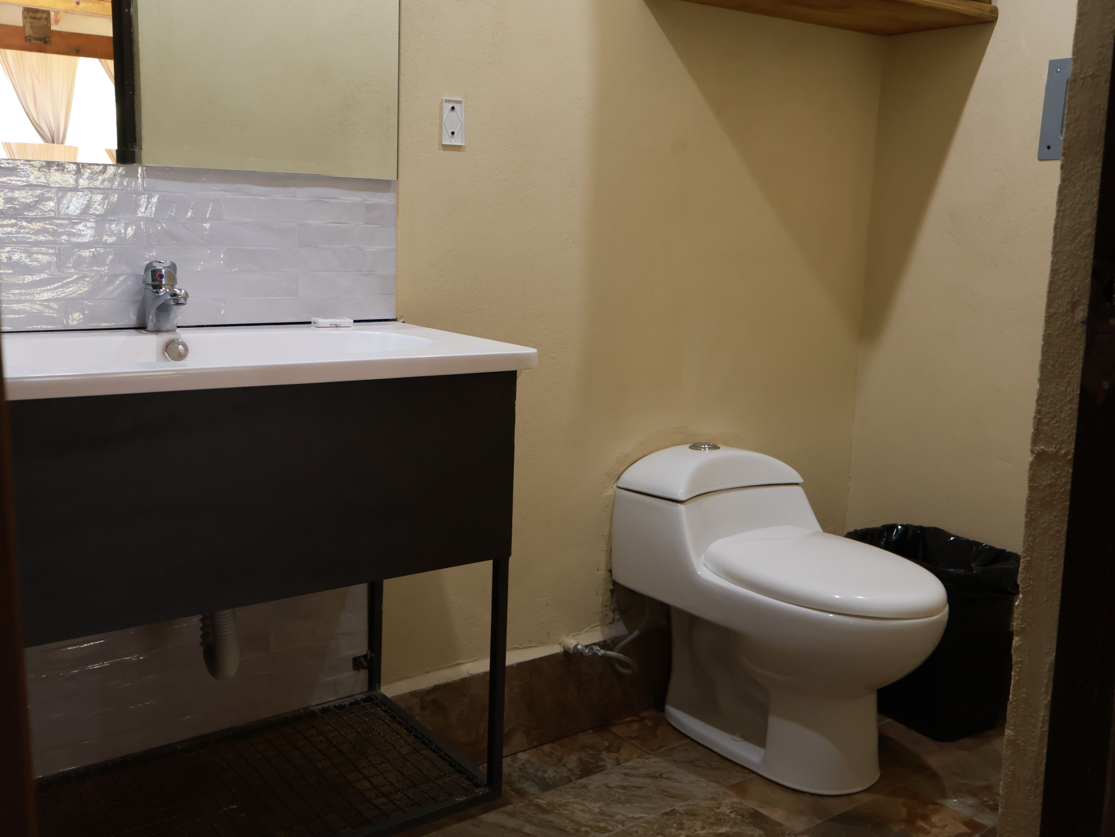 Een badkamer met een witte wastafel, een toilet en een zwarte prullenbak.