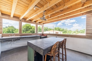 A spacious outdoor kitchen area with a large island, bar stools, and a view of the surrounding greenery. - Hotel Casa Patrón Parras  (Parras de la Fuente)