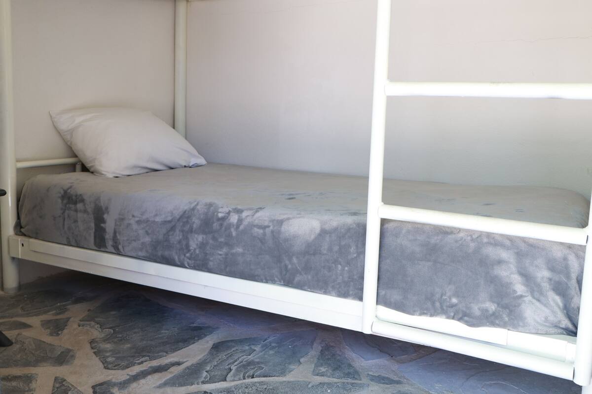 A bunk bed with a grey mattress and white bedding.