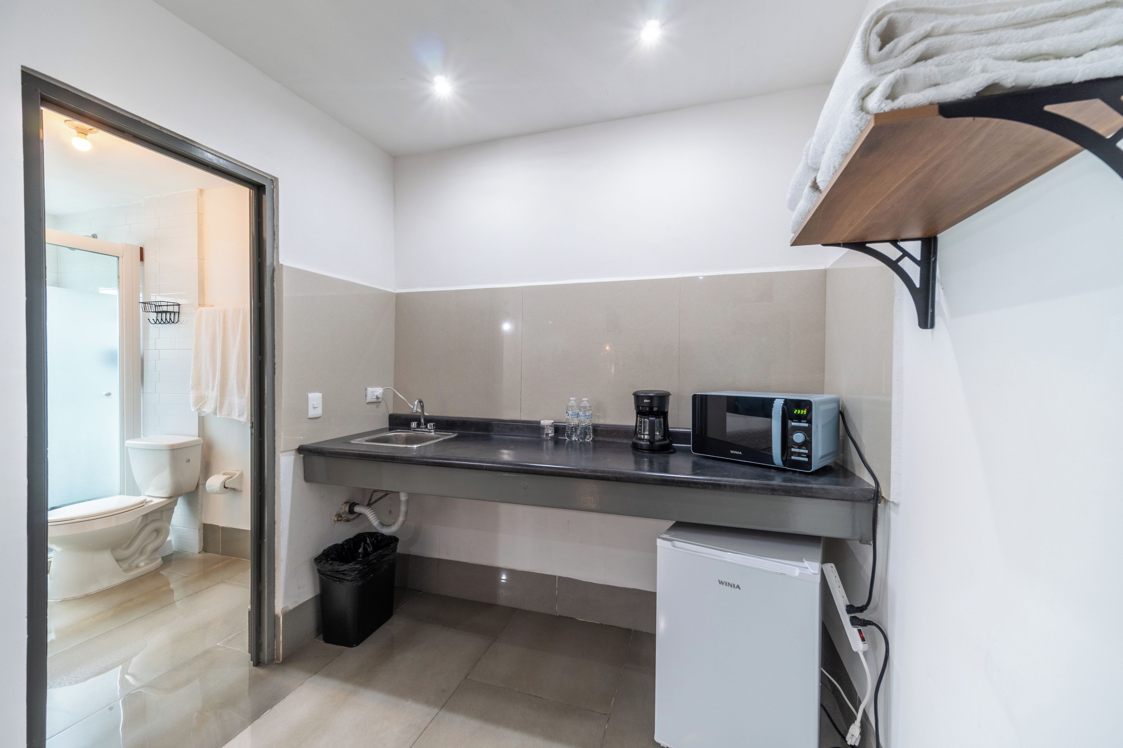 A compact kitchenette with a sink, a microwave, and a small refrigerator.