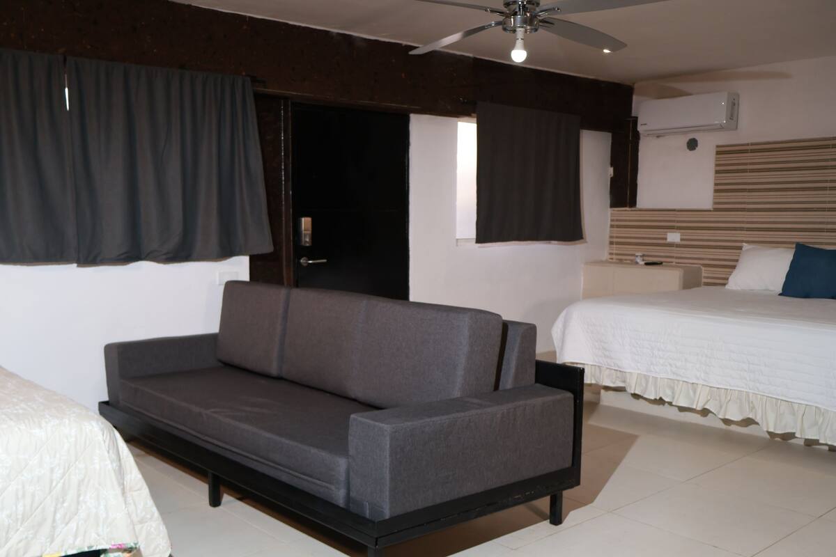A room with a sofa, a bed, a ceiling fan, and an air conditioning unit.