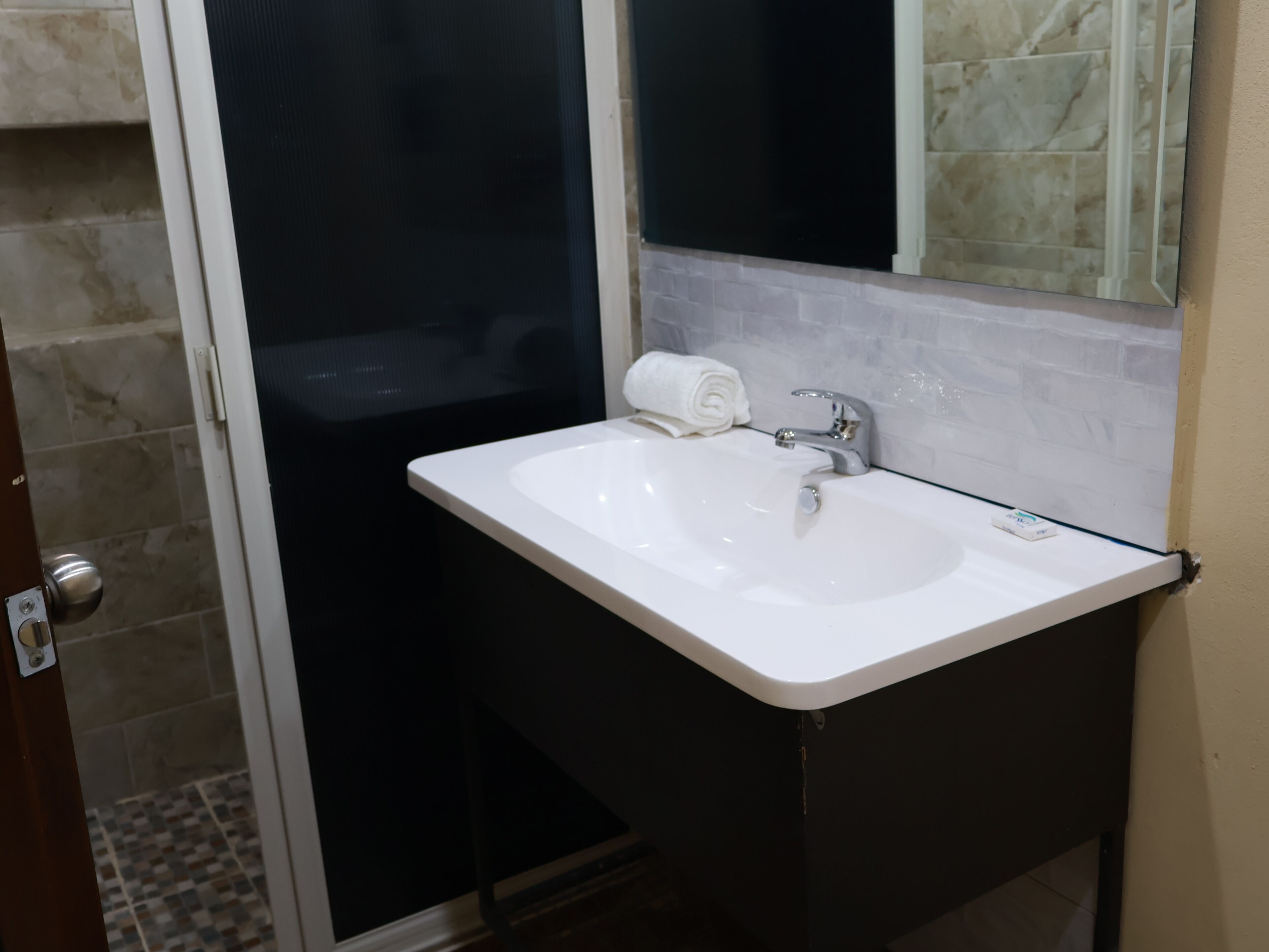 Un baño con lavamanos blanco, un espejo y una toalla.