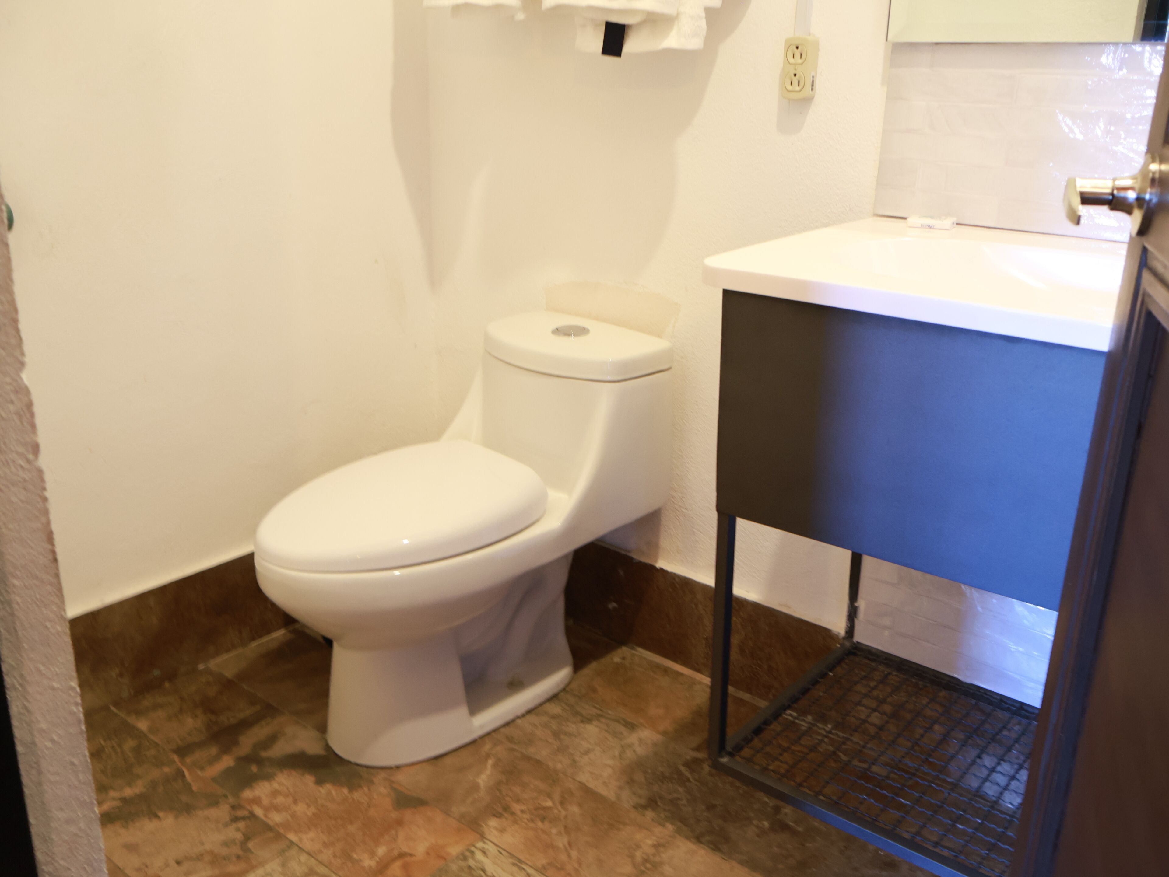 Een badkamer met een wit toilet, een witte wastafel en een metalen plank.