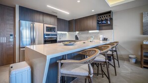 A modern kitchen with a large island, bar stools, stainless steel appliances, and a marble countertop. - Sonoran Star One (Puerto Peñasco)