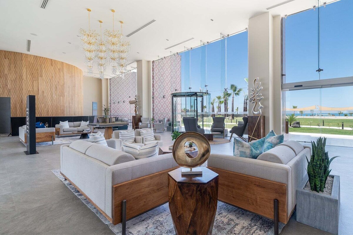 A spacious lobby with a large seating area, a glass enclosure, and a view of the beach.