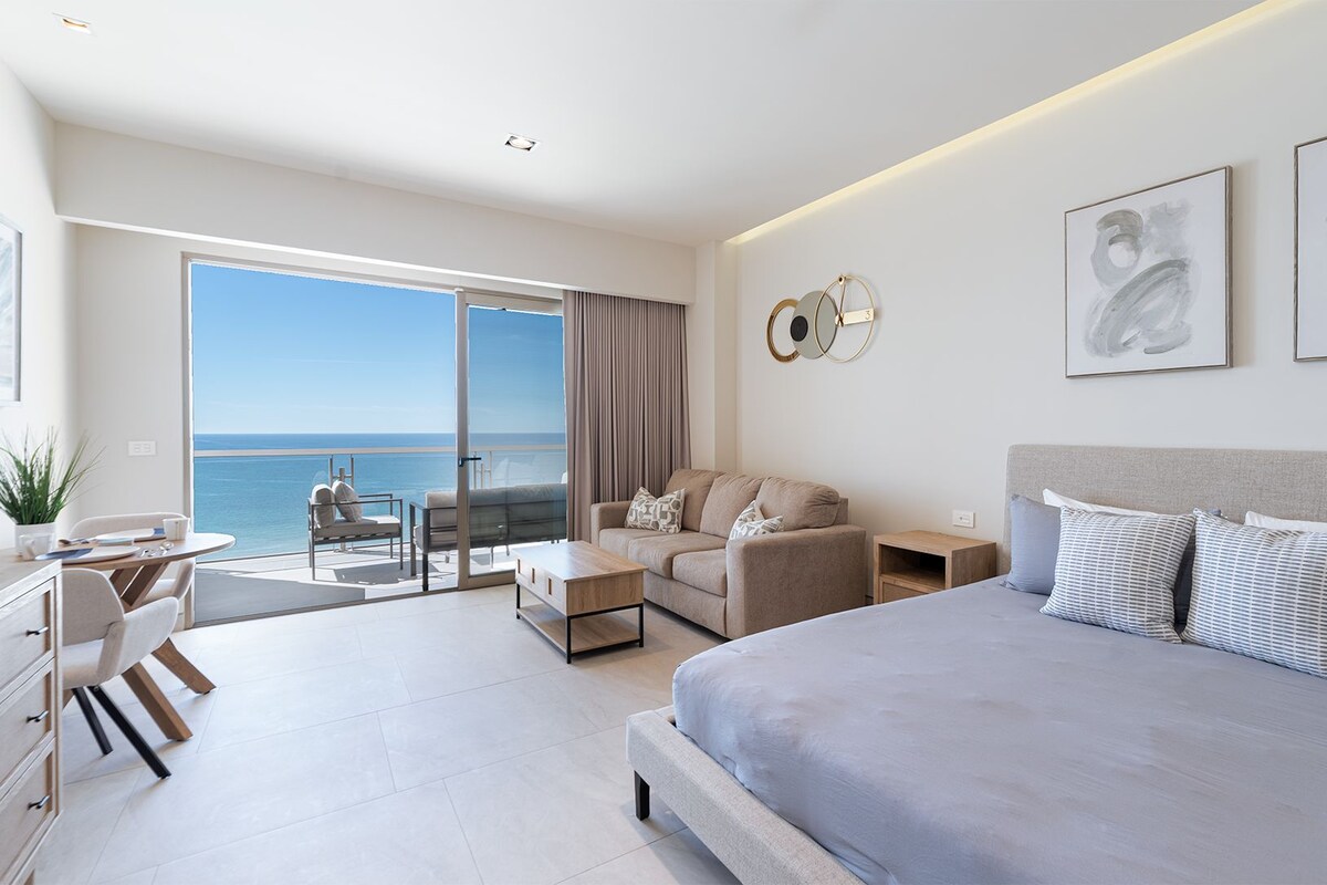 Ein modernes Hotelzimmer mit einem großen Bett, einer Couch, einem Schreibtisch und Blick aufs Meer.