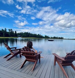 A wooden deck with Adirondack chairs overlooking a calm lake, surrounded by trees. - Serenity Retreat - Mountain Escape- Grandview Peaks (Nebo)